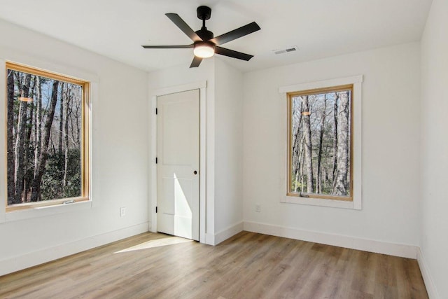 unfurnished room with visible vents, ceiling fan, light wood-style flooring, and baseboards