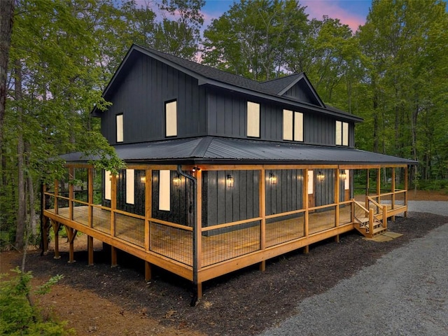 365 Cherokee Cir, Lake Toxaway, NC 28747 - back of house at dusk with board and batten siding, a metal roof, a sunroom, and roof with shingles