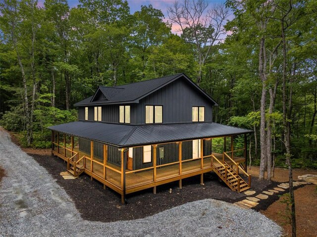 365 Cherokee Cir, Lake Toxaway, NC 28747 - back of house at dusk with board and batten siding, a metal roof, and covered porch