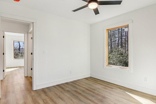 unfurnished room with ceiling fan, light wood-style flooring, and baseboards