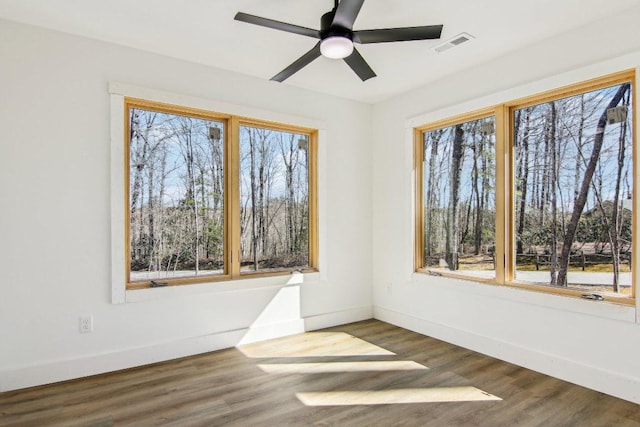 unfurnished room with visible vents, baseboards, ceiling fan, and dark wood-style flooring