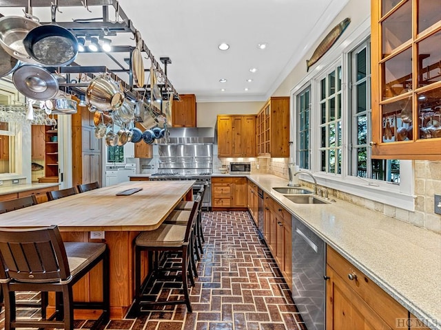 kitchen featuring appliances with stainless steel finishes, tasteful backsplash, butcher block counters, sink, and a kitchen bar