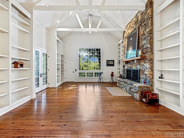 unfurnished room with a fireplace, french doors, built in shelves, ceiling fan, and hardwood / wood-style floors