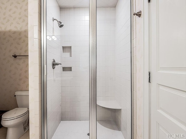 bathroom with a shower with shower door and toilet