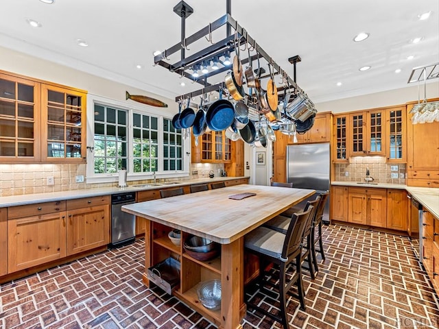 kitchen with sink, decorative light fixtures, stainless steel built in refrigerator, and ornamental molding