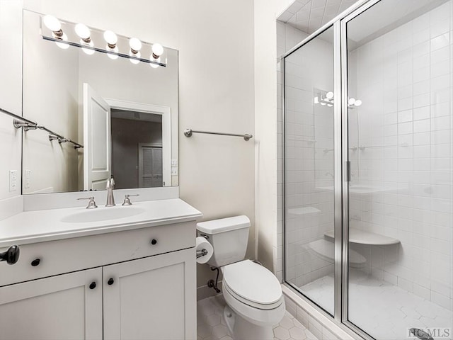 bathroom with toilet, vanity, and a shower with shower door