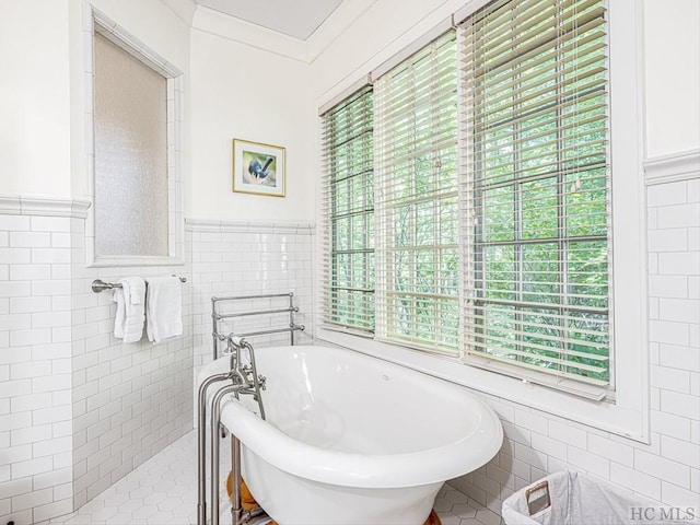 bathroom with ornamental molding, tile walls, and a bathtub