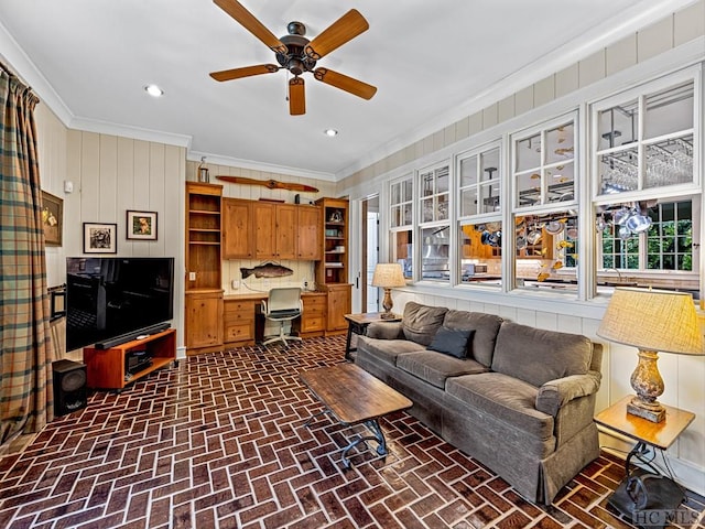 living room featuring ceiling fan, built in desk, and ornamental molding