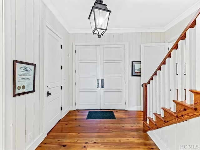 entryway with an inviting chandelier, hardwood / wood-style flooring, and ornamental molding