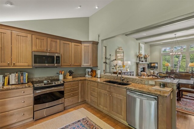72 Winterberry Ct Unit 7, Highlands, NC 28741 - kitchen with appliances with stainless steel finishes, a peninsula, open floor plan, light stone counters, and light wood-type flooring