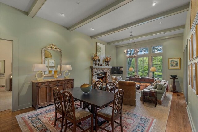 72 Winterberry Ct Unit 7, Highlands, NC 28741 - dining area featuring light wood-style flooring, beam ceiling, a warm lit fireplace, and a chandelier