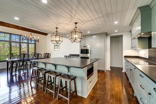 kitchen with wooden ceiling, appliances with stainless steel finishes, dark hardwood / wood-style flooring, a kitchen island, and pendant lighting