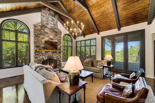 sunroom / solarium with a healthy amount of sunlight, a stone fireplace, vaulted ceiling with beams, and a chandelier