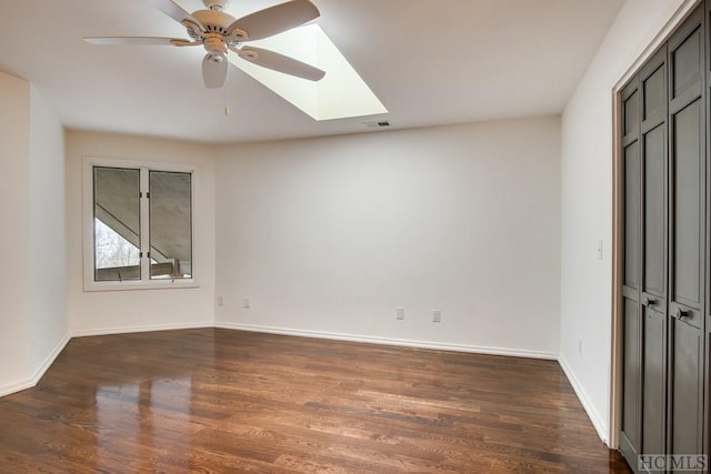 unfurnished bedroom featuring ceiling fan, dark hardwood / wood-style floors, a skylight, and a closet