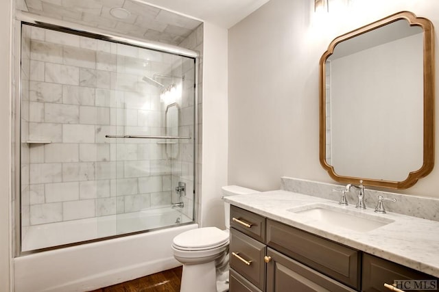 full bathroom featuring vanity, hardwood / wood-style flooring, shower / bath combination with glass door, and toilet