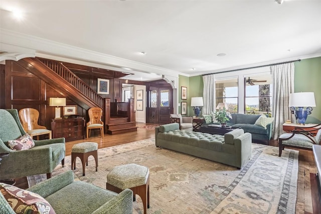 living area with ornamental molding, wood finished floors, and stairway