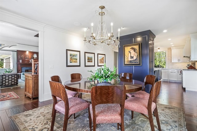dining space featuring dark wood finished floors, a chandelier, crown molding, and recessed lighting