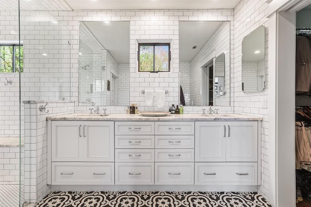 bathroom with tile walls, tiled shower, double vanity, and a walk in closet