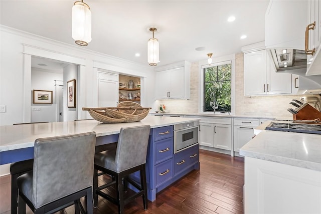 kitchen featuring a sink, blue cabinets, white cabinetry, decorative backsplash, and recessed lighting
