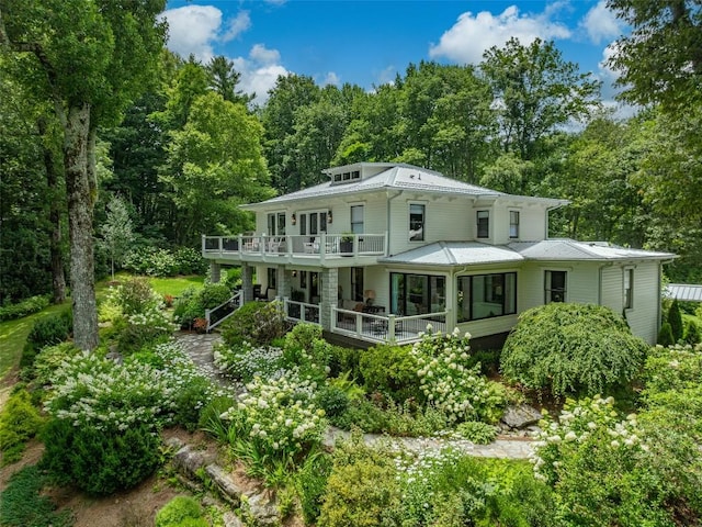 back of house featuring a wooded view, a deck, and a balcony