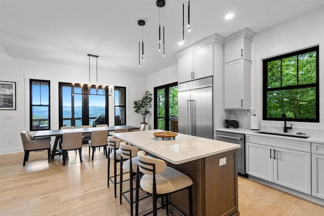 55 Steeplebush Ct, Tuckasegee, NC 28783 - kitchen with appliances with stainless steel finishes, a center island, light wood finished floors, light stone counters, and hanging light fixtures