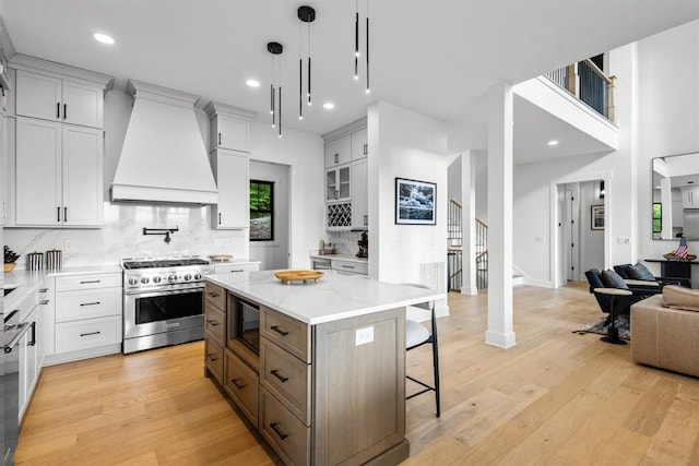 55 Steeplebush Ct, Tuckasegee, NC 28783 - kitchen with high end stove, custom range hood, a breakfast bar area, open floor plan, and light wood-style flooring