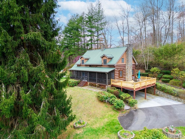 view of front facade with a sunroom, a wooden deck, and a front yard