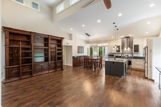 314 Beckonridge Trl, Sapphire, NC 28774 - kitchen with an island with sink, appliances with stainless steel finishes, a ceiling fan, wall chimney exhaust hood, and dark wood-style flooring