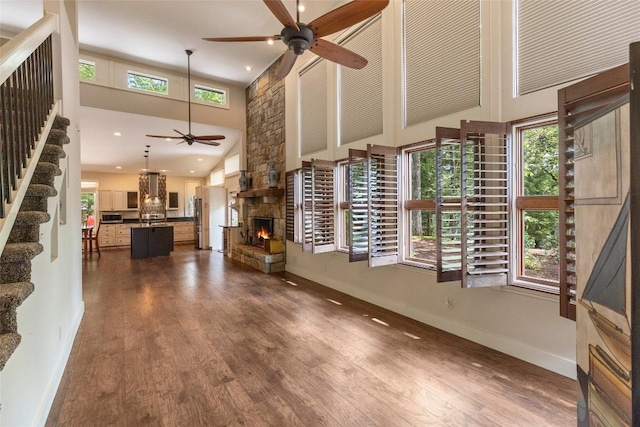 314 Beckonridge Trl, Sapphire, NC 28774 - unfurnished living room featuring a ceiling fan, a towering ceiling, a fireplace, stairs, and dark wood-style floors