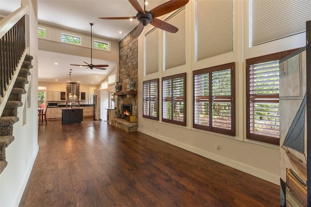 314 Beckonridge Trl, Sapphire, NC 28774 - unfurnished living room with a ceiling fan, a high ceiling, a stone fireplace, dark wood-type flooring, and stairs