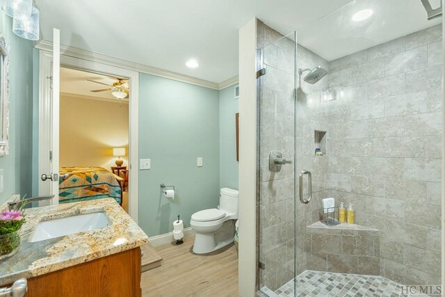 bathroom with hardwood / wood-style floors, vanity, an enclosed shower, ceiling fan, and toilet