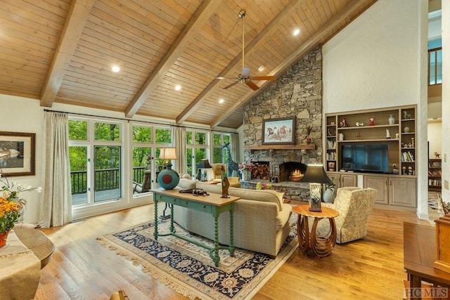 living room with beam ceiling, a stone fireplace, light hardwood / wood-style flooring, and high vaulted ceiling