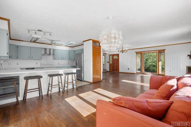 living room with crown molding, dark hardwood / wood-style floors, ceiling fan with notable chandelier, and sink