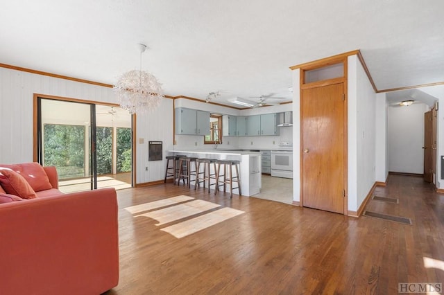 unfurnished living room featuring crown molding, sink, ceiling fan with notable chandelier, and hardwood / wood-style floors