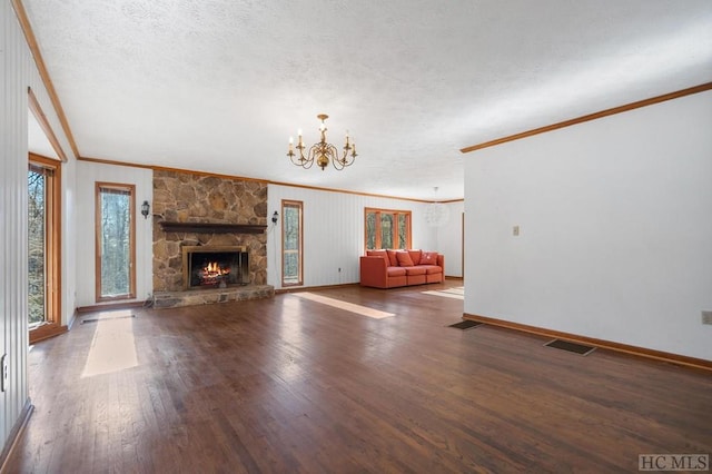 unfurnished living room featuring crown molding, dark wood-type flooring, a textured ceiling, a stone fireplace, and a chandelier