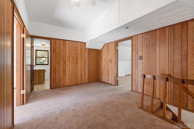 bonus room featuring wooden walls, light colored carpet, and ceiling fan