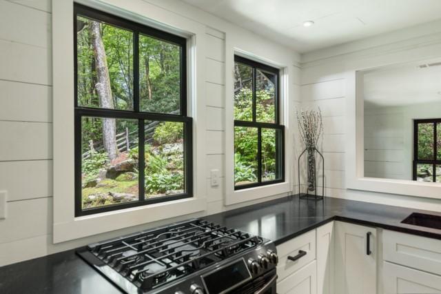kitchen with black gas stove, dark countertops, and white cabinets