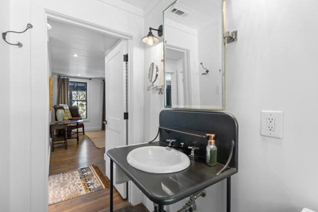 bathroom with wood finished floors, a sink, and visible vents