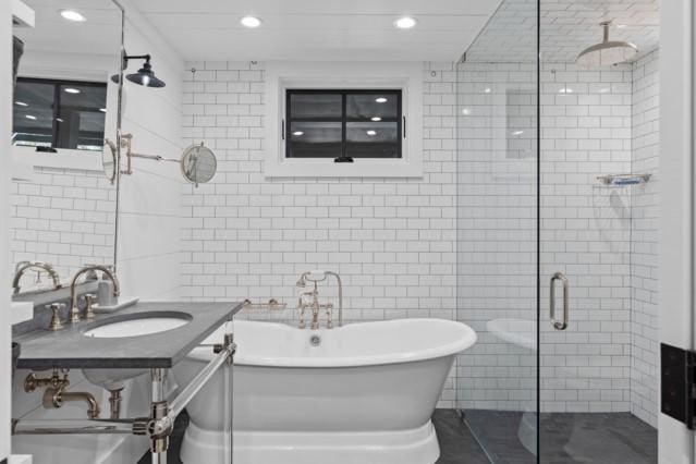 bathroom featuring a freestanding tub, a stall shower, recessed lighting, tile walls, and a sink