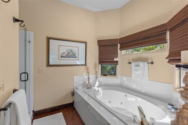 full bath with a stall shower, baseboards, a tub with jets, and wood finished floors