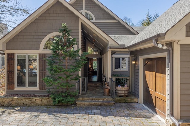 view of exterior entry with a shingled roof