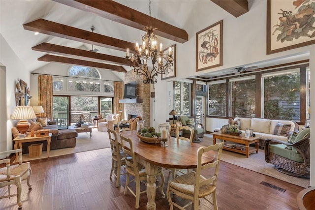 dining room with wood finished floors, a fireplace, visible vents, and high vaulted ceiling