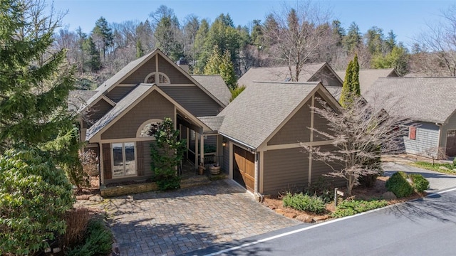 view of front of house featuring an attached garage, driveway, and roof with shingles