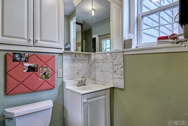 bathroom with toilet, vanity, and tasteful backsplash