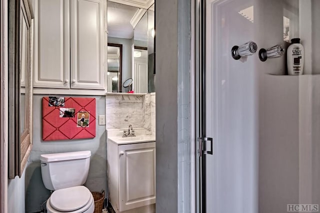 bathroom with toilet, vanity, and tasteful backsplash