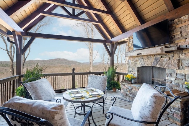 deck with an outdoor stone fireplace and a gazebo