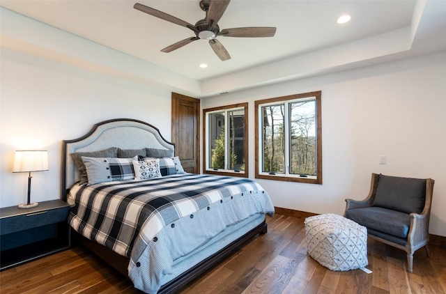 bedroom featuring recessed lighting, baseboards, wood finished floors, and a raised ceiling