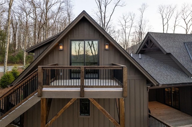 back of property with board and batten siding, a deck, and roof with shingles