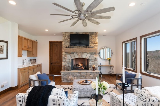 living room featuring baseboards, ceiling fan, wood finished floors, and a fireplace