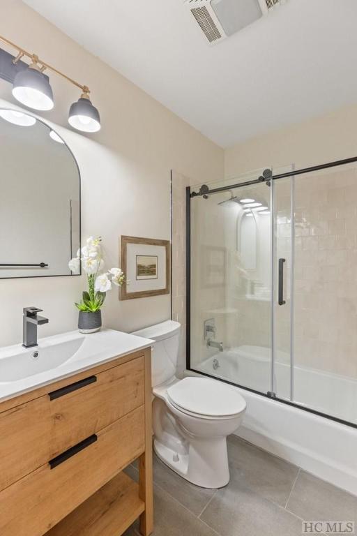 full bathroom featuring vanity, bath / shower combo with glass door, tile patterned floors, and toilet